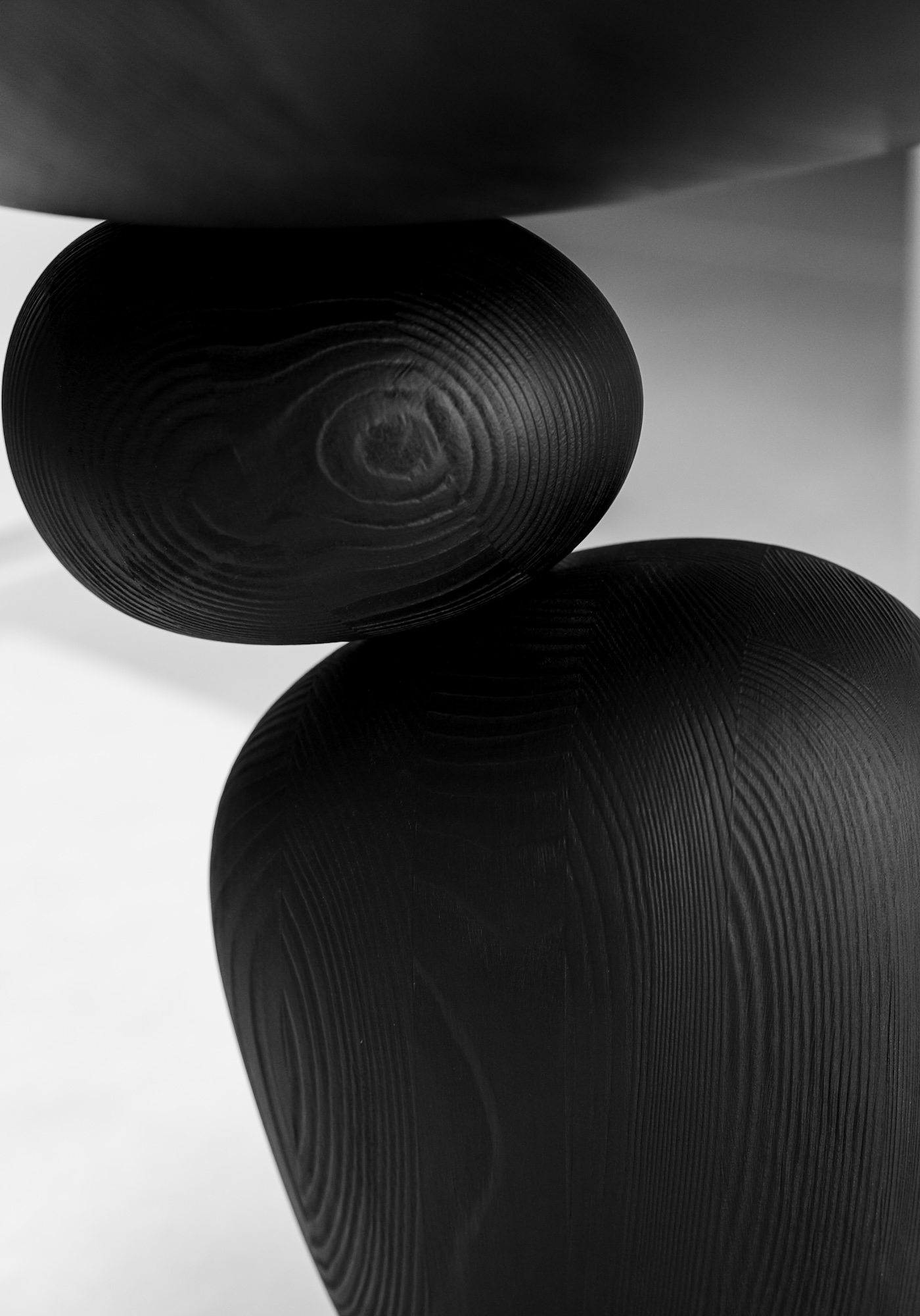 Schwarz gebeizte Holzvolumen des Beistelltischs LIGNA in scheinbar schwebender Balance